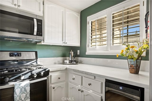 kitchen with white cabinets, beverage cooler, and appliances with stainless steel finishes