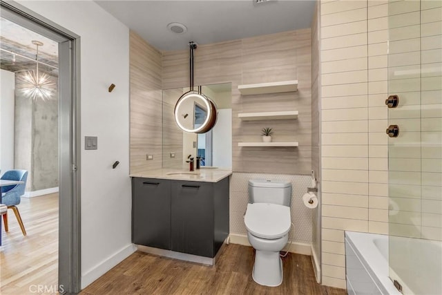 bathroom featuring a washtub, vanity, tile walls, hardwood / wood-style floors, and toilet