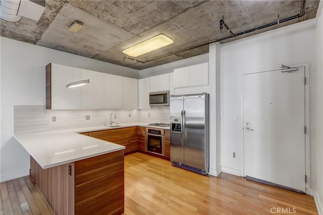 kitchen with white cabinetry, sink, appliances with stainless steel finishes, and light hardwood / wood-style flooring