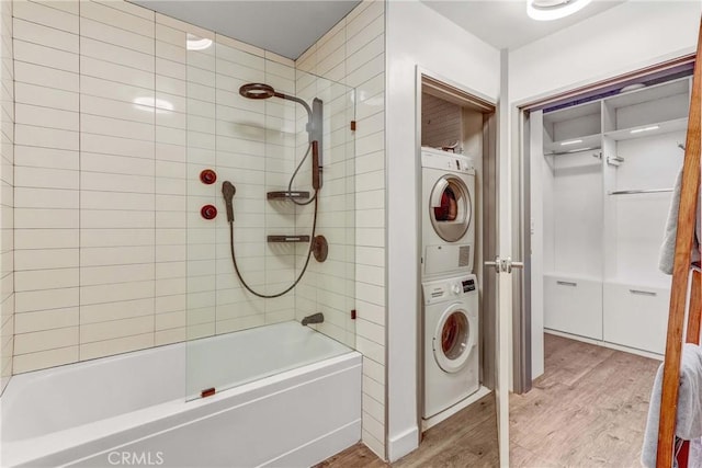 bathroom featuring hardwood / wood-style floors, stacked washer and dryer, and tiled shower / bath