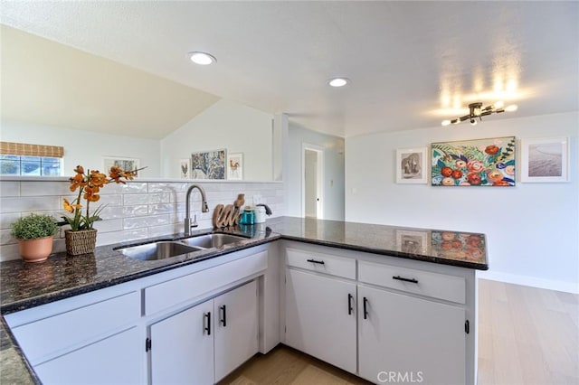 kitchen with white cabinets, kitchen peninsula, light hardwood / wood-style flooring, and tasteful backsplash