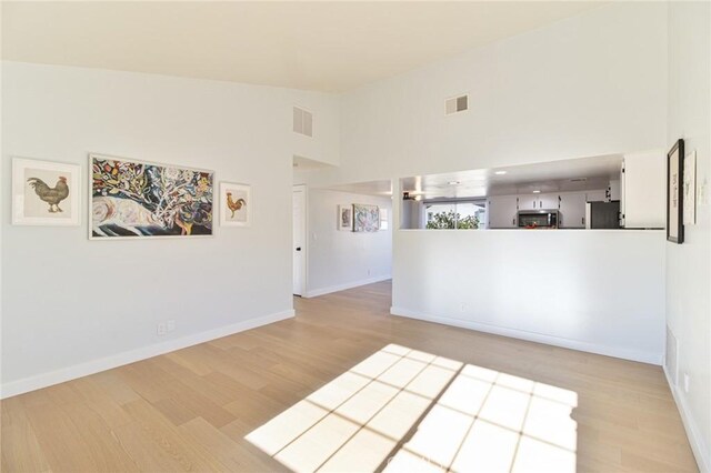 6556 Lupine Ave Unit 29, Palms, CA 92277 - empty room with light wood-type flooring, baseboards, and high vaulted ceiling