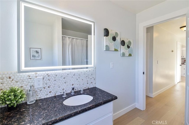 bathroom with hardwood / wood-style floors, decorative backsplash, and vanity