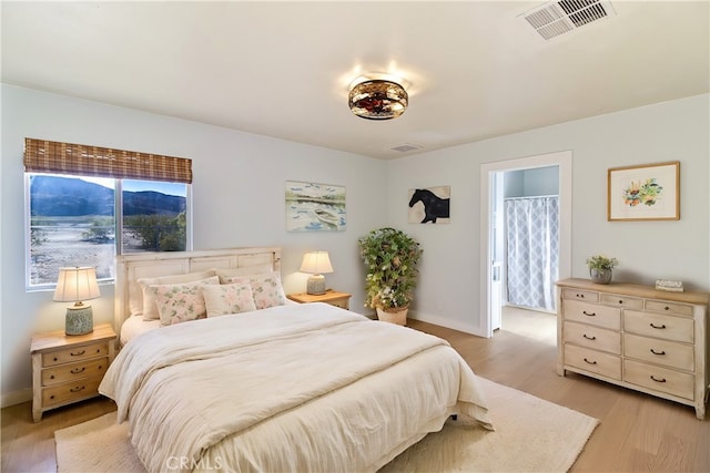 bedroom with light wood-type flooring and ensuite bathroom