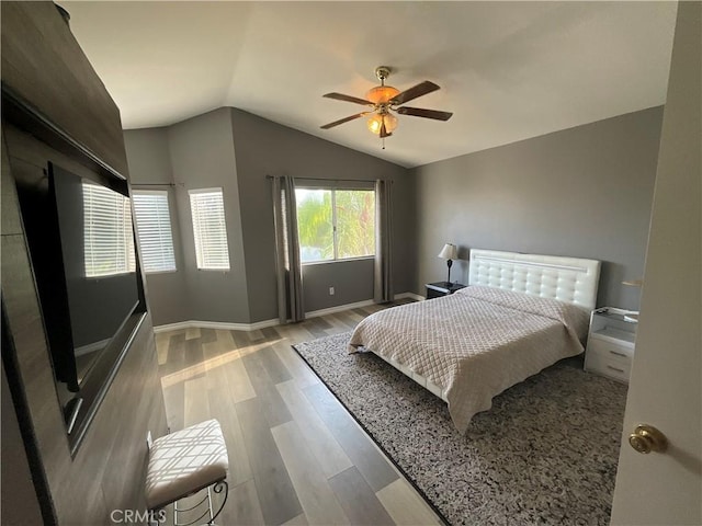 bedroom with ceiling fan, light wood-type flooring, and vaulted ceiling