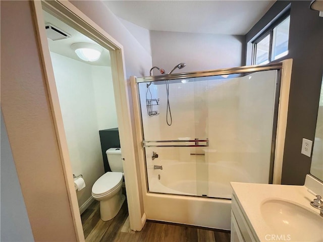 full bathroom with hardwood / wood-style floors, vanity, toilet, and bath / shower combo with glass door