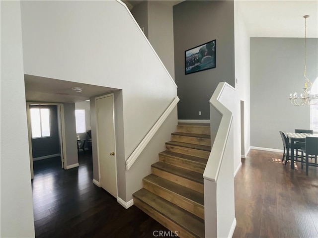 stairs with an inviting chandelier, a high ceiling, and hardwood / wood-style flooring