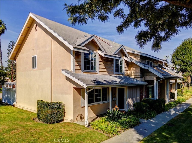 view of front of house featuring a shingled roof, a front lawn, and stucco siding