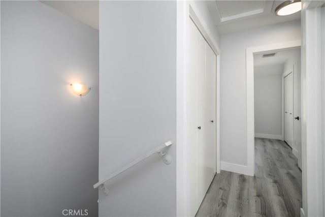 corridor with an upstairs landing, visible vents, light wood-style flooring, and baseboards