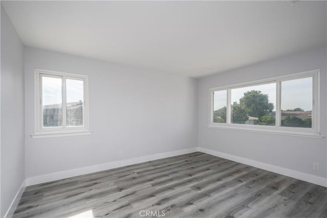 spare room with a healthy amount of sunlight, light wood-type flooring, and baseboards