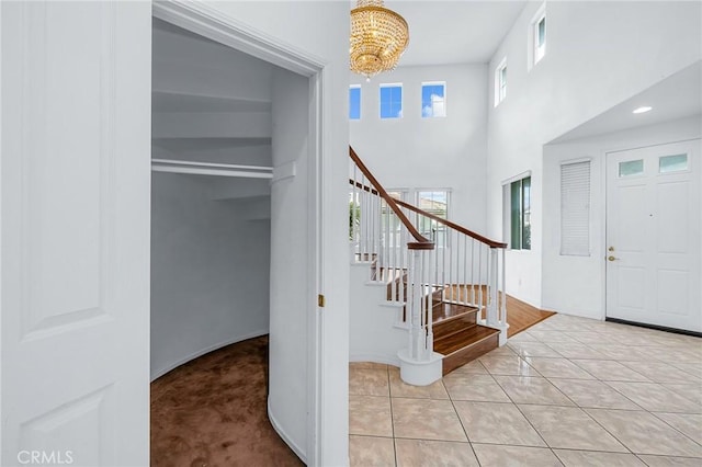 foyer with a chandelier, a towering ceiling, and light colored carpet