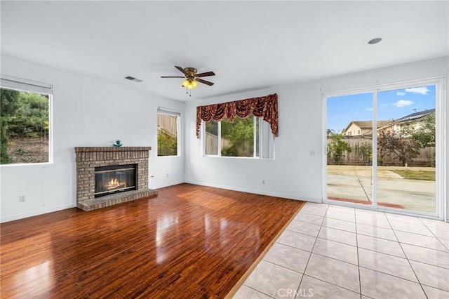 unfurnished living room featuring a fireplace, light hardwood / wood-style floors, and ceiling fan