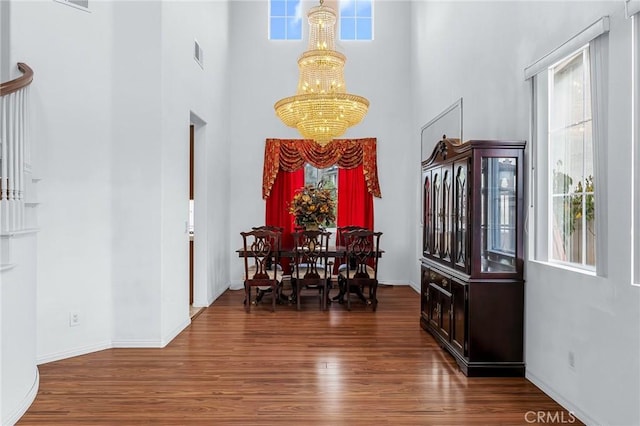 foyer with a towering ceiling, an inviting chandelier, and dark wood-type flooring