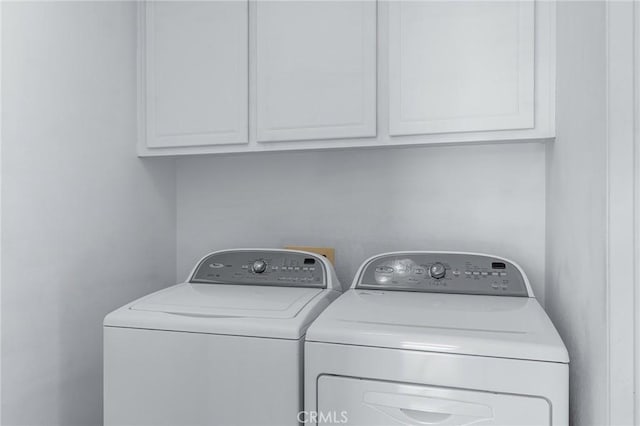 washroom with washing machine and dryer and cabinets