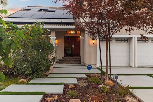 exterior entry at dusk with solar panels and a garage