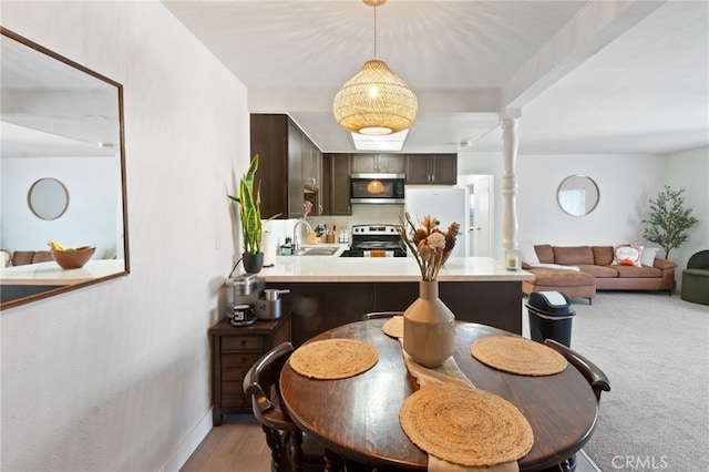 carpeted dining area featuring decorative columns and sink