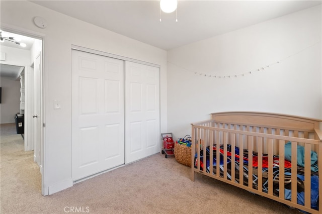 bedroom featuring a closet, light colored carpet, and a nursery area