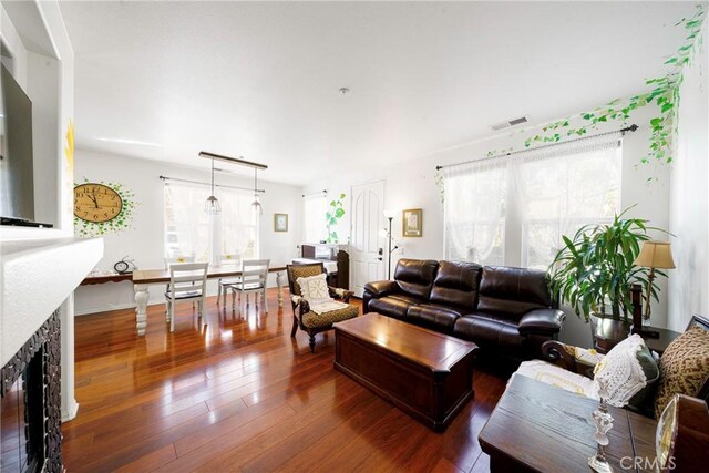 living room featuring dark hardwood / wood-style flooring, a stone fireplace, and plenty of natural light