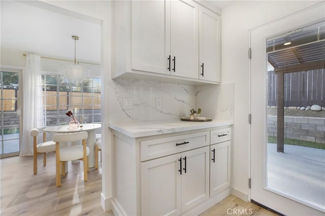 bar with a chandelier, white cabinetry, pendant lighting, and light wood-type flooring