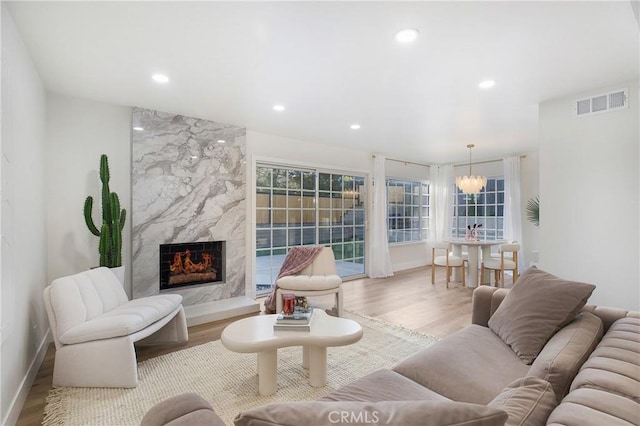 living room with a premium fireplace, light hardwood / wood-style floors, and an inviting chandelier