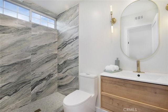 bathroom featuring a tile shower, vanity, and toilet