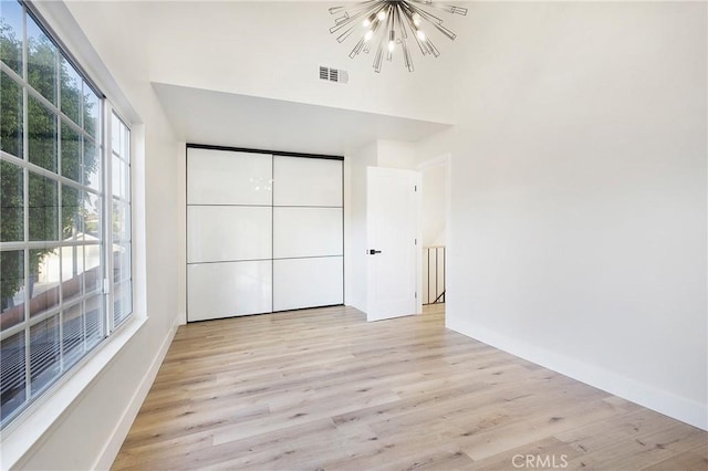 unfurnished bedroom featuring light hardwood / wood-style floors and an inviting chandelier