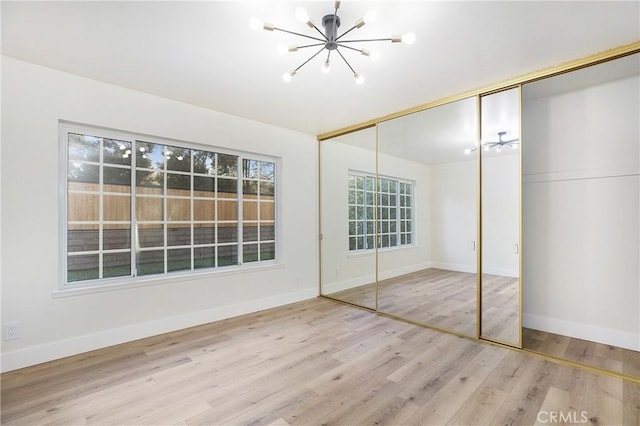 unfurnished bedroom featuring hardwood / wood-style floors, a closet, and a notable chandelier