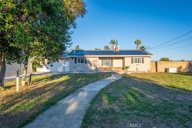 ranch-style house with a front lawn, a garage, and solar panels