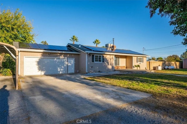 ranch-style home with solar panels, a front lawn, and a garage