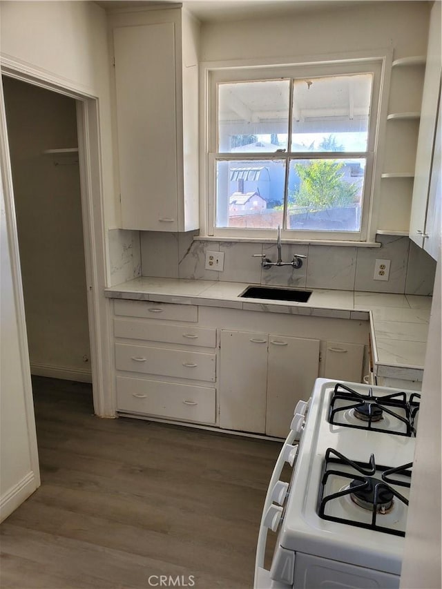 kitchen featuring white cabinets, decorative backsplash, white gas range, and sink