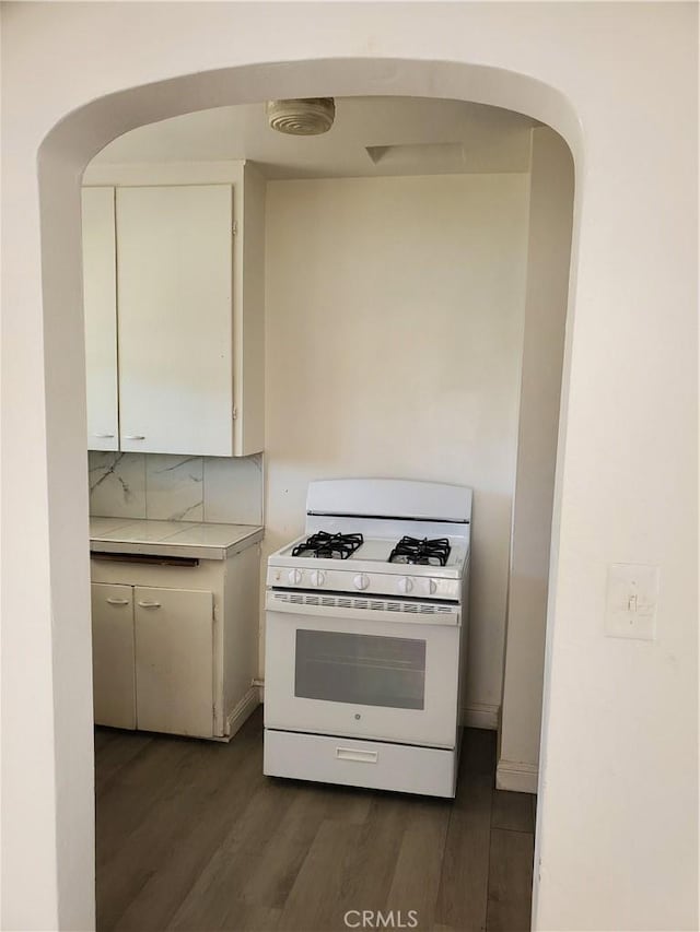 kitchen featuring backsplash, white cabinets, dark wood-type flooring, and white range with gas cooktop