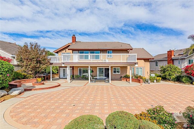 rear view of property featuring a balcony and a patio