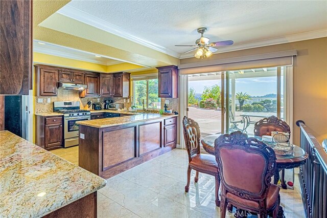 kitchen with stainless steel gas stove, tasteful backsplash, light stone countertops, a textured ceiling, and kitchen peninsula