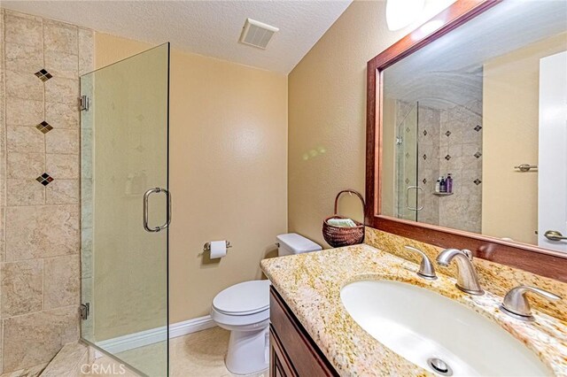 bathroom featuring a shower with door, vanity, a textured ceiling, tile patterned floors, and toilet