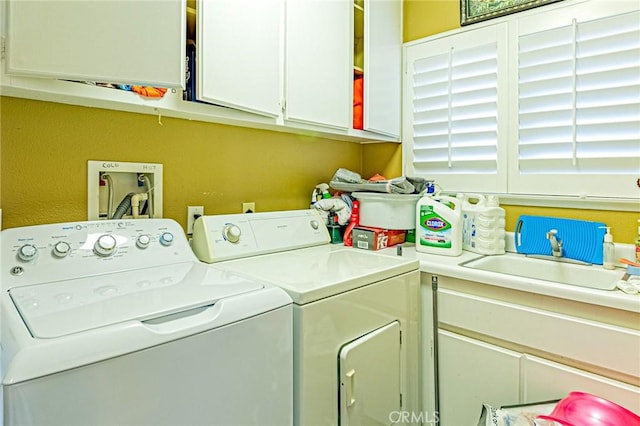 clothes washing area featuring cabinets, sink, and washing machine and dryer