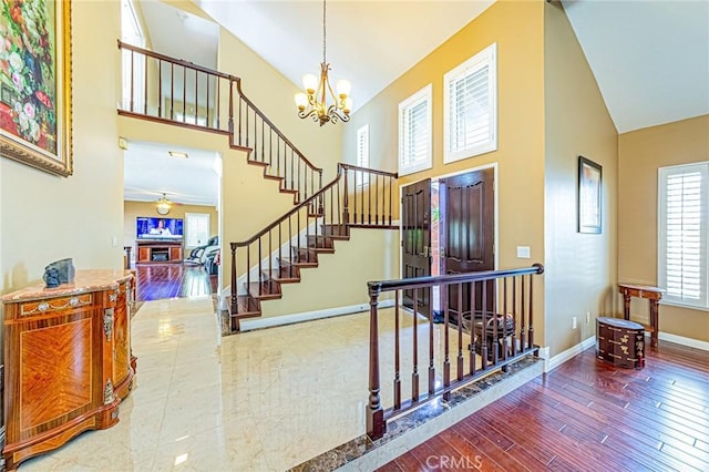 foyer entrance featuring a notable chandelier, hardwood / wood-style flooring, and high vaulted ceiling