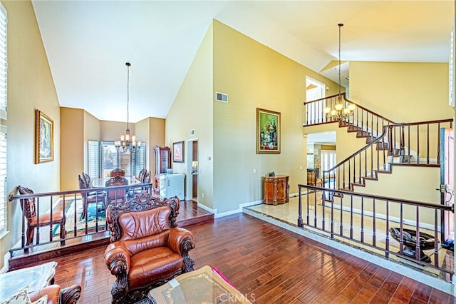 living room with dark hardwood / wood-style flooring, a notable chandelier, and high vaulted ceiling