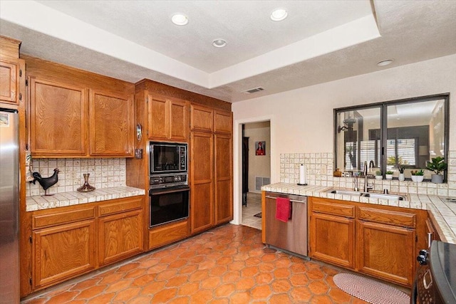 kitchen featuring sink, backsplash, a tray ceiling, and black appliances