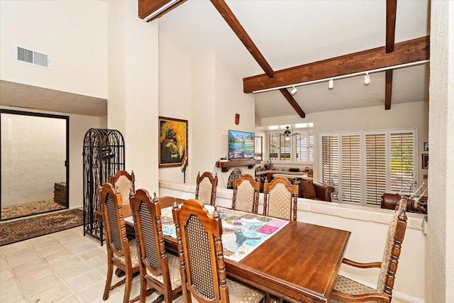 dining space with ceiling fan, rail lighting, beam ceiling, and high vaulted ceiling