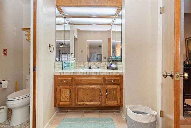 bathroom with toilet, vanity, backsplash, and tile patterned floors