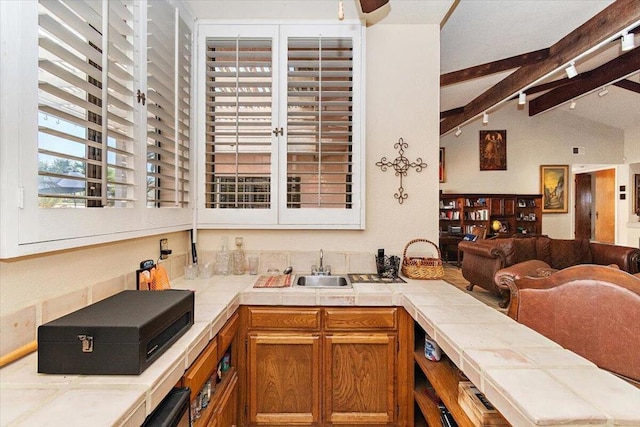 kitchen with vaulted ceiling with beams, sink, and tile countertops