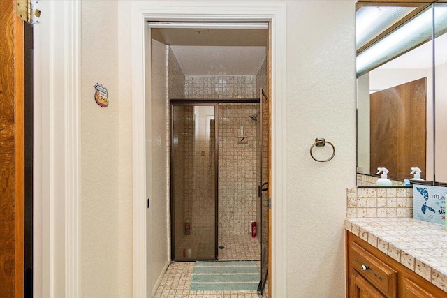 bathroom featuring a shower with shower door, vanity, and tasteful backsplash