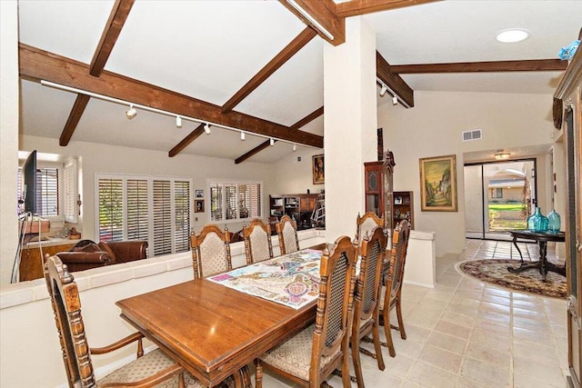 dining space with light tile patterned flooring, rail lighting, and lofted ceiling with beams