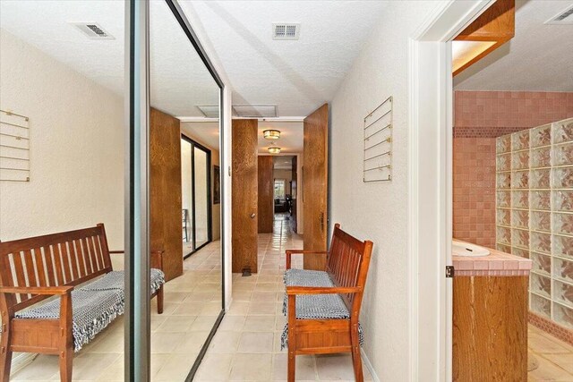 corridor with a textured ceiling and light tile patterned flooring