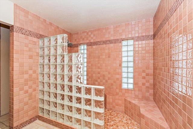 bathroom with tile walls, a tile shower, and tile patterned flooring