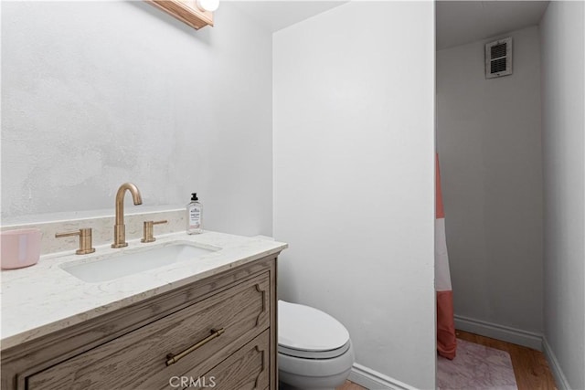 bathroom with hardwood / wood-style floors, vanity, and toilet