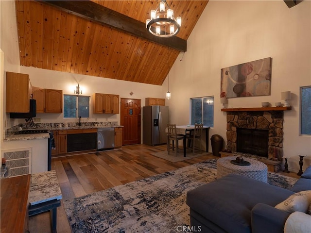 living room featuring high vaulted ceiling, a stone fireplace, hardwood / wood-style flooring, beamed ceiling, and a notable chandelier