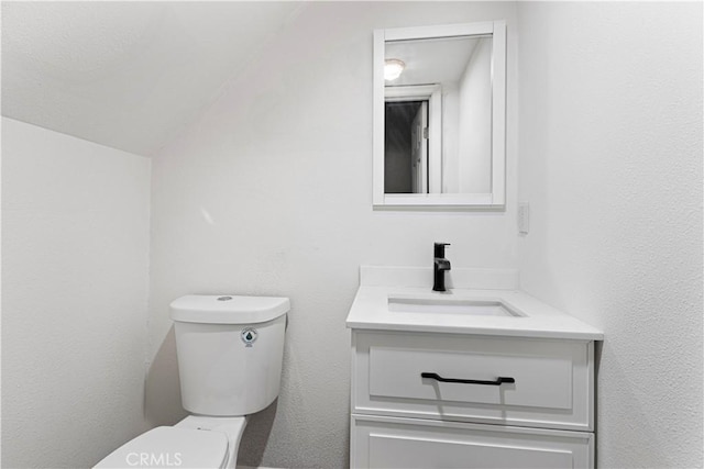 bathroom with vanity, lofted ceiling, and toilet