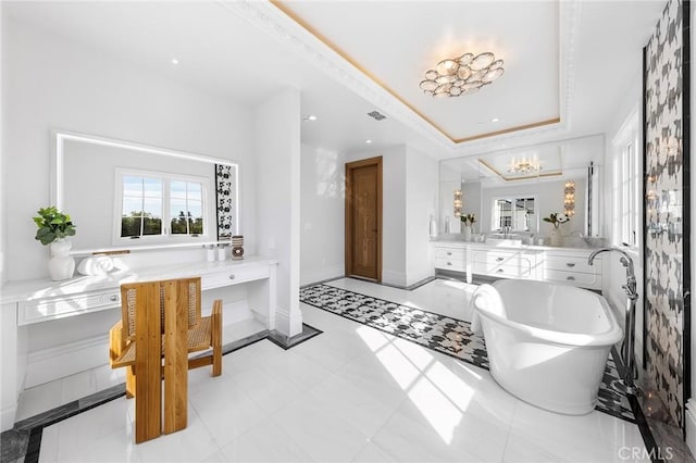 bathroom featuring tile patterned floors, a washtub, vanity, a tray ceiling, and a notable chandelier