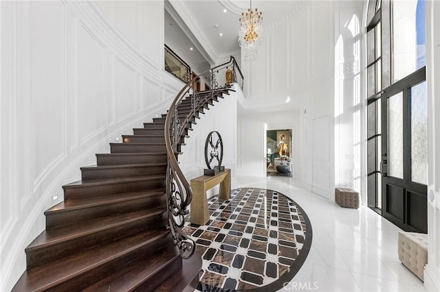 interior space with french doors, a towering ceiling, light tile patterned floors, and a notable chandelier